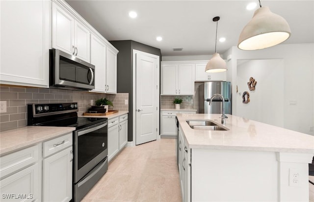 3740 Passion Vine Dr, Alva, FL 33920 - kitchen featuring appliances with stainless steel finishes, a sink, a kitchen island with sink, backsplash, and white cabinets