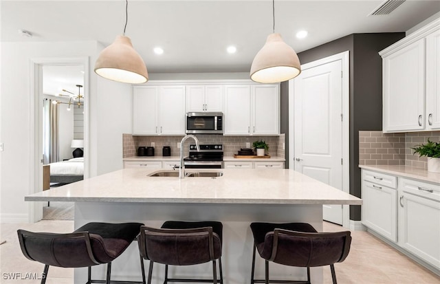 3740 Passion Vine Dr, Alva, FL 33920 - kitchen with appliances with stainless steel finishes, a kitchen bar, a sink, white cabinets, and tasteful backsplash