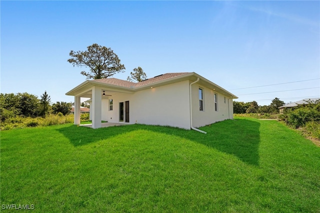 908 Barcia St E, Lehigh Acres, FL 33974 - rear view of house featuring a lawn, a patio, and stucco siding