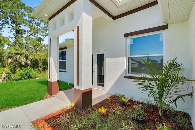 908 Barcia St E, Lehigh Acres, FL 33974 - doorway to property featuring stucco siding and a lawn
