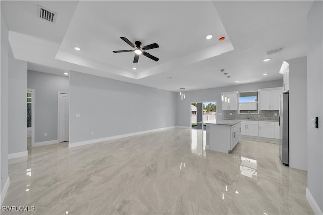 908 Barcia St E, Lehigh Acres, FL 33974 - unfurnished living room featuring ceiling fan, a tray ceiling, a sink, baseboards, and recessed lighting
