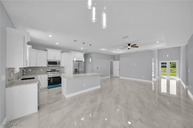908 Barcia St E, Lehigh Acres, FL 33974 - kitchen featuring appliances with stainless steel finishes, a tray ceiling, tasteful backsplash, a center island, and a sink