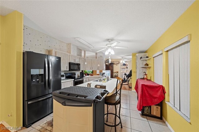 919 Manatee Rd, Naples, FL 34114 - kitchen with black appliances, ceiling fan, an island with sink, light tile patterned floors, and a textured ceiling