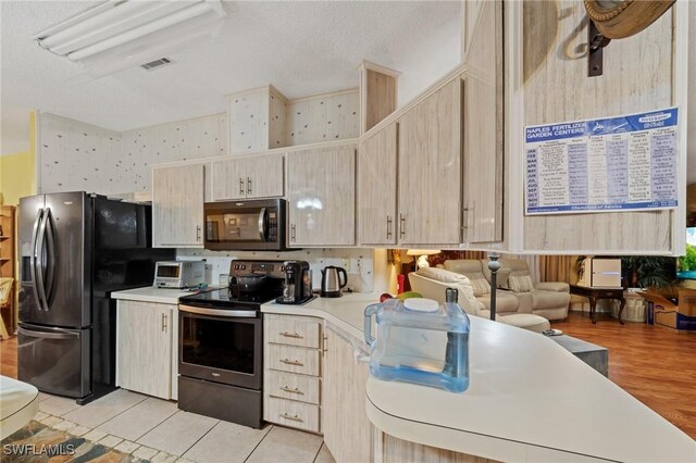 919 Manatee Rd, Naples, FL 34114 - kitchen featuring stainless steel appliances, light countertops, light brown cabinetry, and a textured ceiling