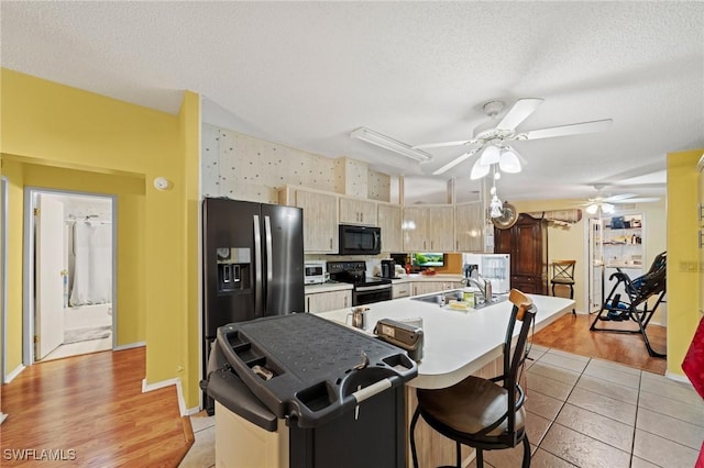 919 Manatee Rd, Naples, FL 34114 - kitchen with stainless steel appliances, a ceiling fan, a textured ceiling, light countertops, and a center island with sink