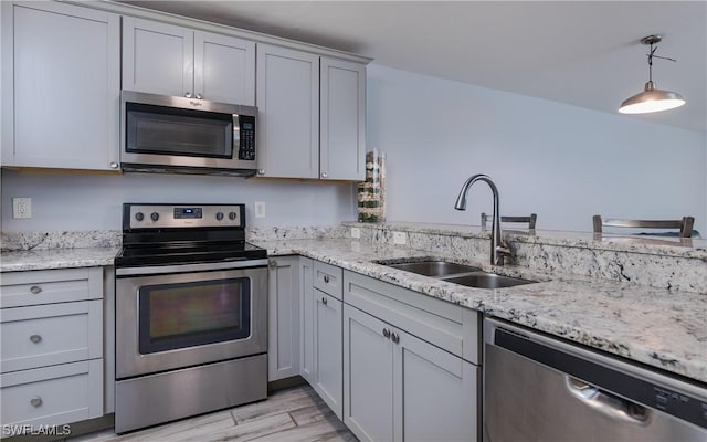 3451 County Barn Rd Unit G103, Naples, FL 34112 - kitchen with appliances with stainless steel finishes, light wood-style floors, light stone countertops, and pendant lighting