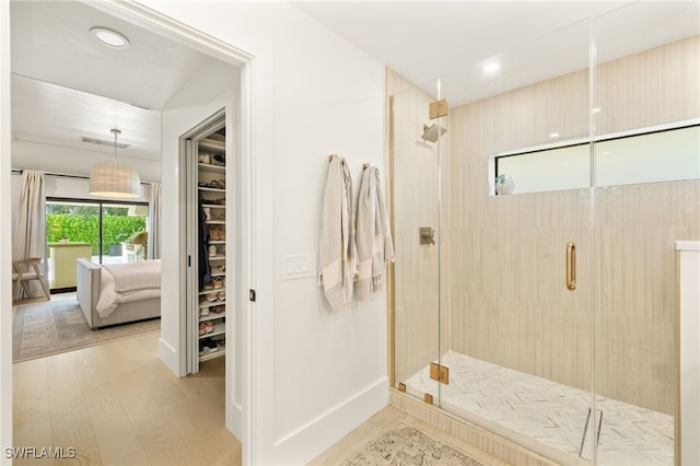 7658 Ponte Verde Way, Naples, FL 34109 - ensuite bathroom featuring a stall shower, a walk in closet, recessed lighting, and wood finished floors