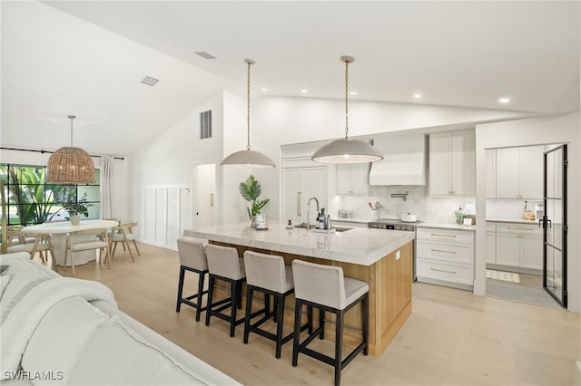 7658 Ponte Verde Way, Naples, FL 34109 - kitchen featuring open floor plan, high vaulted ceiling, a kitchen bar, light wood-style flooring, and a large island