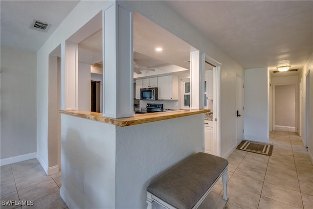 5549 Westwind Ln, Fort Myers, FL 33919 - kitchen featuring stove, stainless steel microwave, light tile patterned floors, and white cabinets