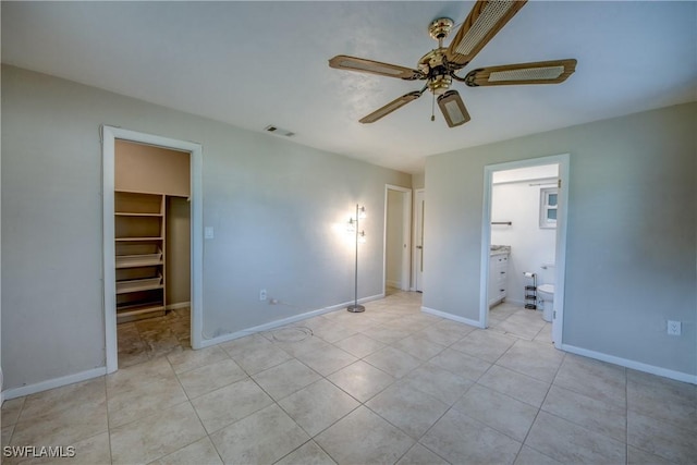 5549 Westwind Ln, Fort Myers, FL 33919 - unfurnished bedroom featuring a spacious closet, a closet, a ceiling fan, ensuite bath, and light tile patterned flooring