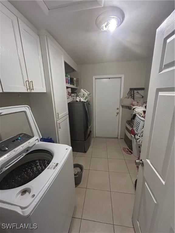 4920 Cortez Cir, Naples, FL 34112 - washroom featuring washer / dryer, cabinet space, and light tile patterned flooring