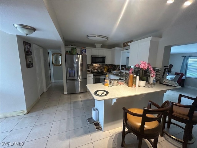 4920 Cortez Cir, Naples, FL 34112 - kitchen featuring stainless steel appliances, a peninsula, backsplash, and light tile patterned floors