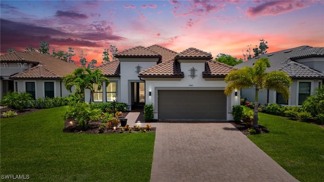 17467 Caravita Ln, Fort Myers, FL 33913 - mediterranean / spanish home featuring an attached garage, stucco siding, a tiled roof, driveway, and a yard
