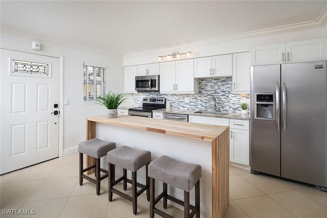 960 7th St S Unit 202, Naples, FL 34102 - kitchen featuring appliances with stainless steel finishes, wooden counters, a breakfast bar area, light tile patterned floors, and crown molding
