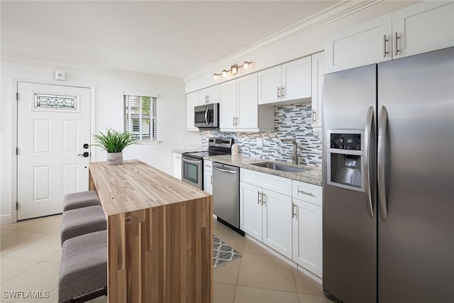 960 7th St S Unit 202, Naples, FL 34102 - kitchen with appliances with stainless steel finishes, light tile patterned flooring, butcher block countertops, backsplash, and crown molding