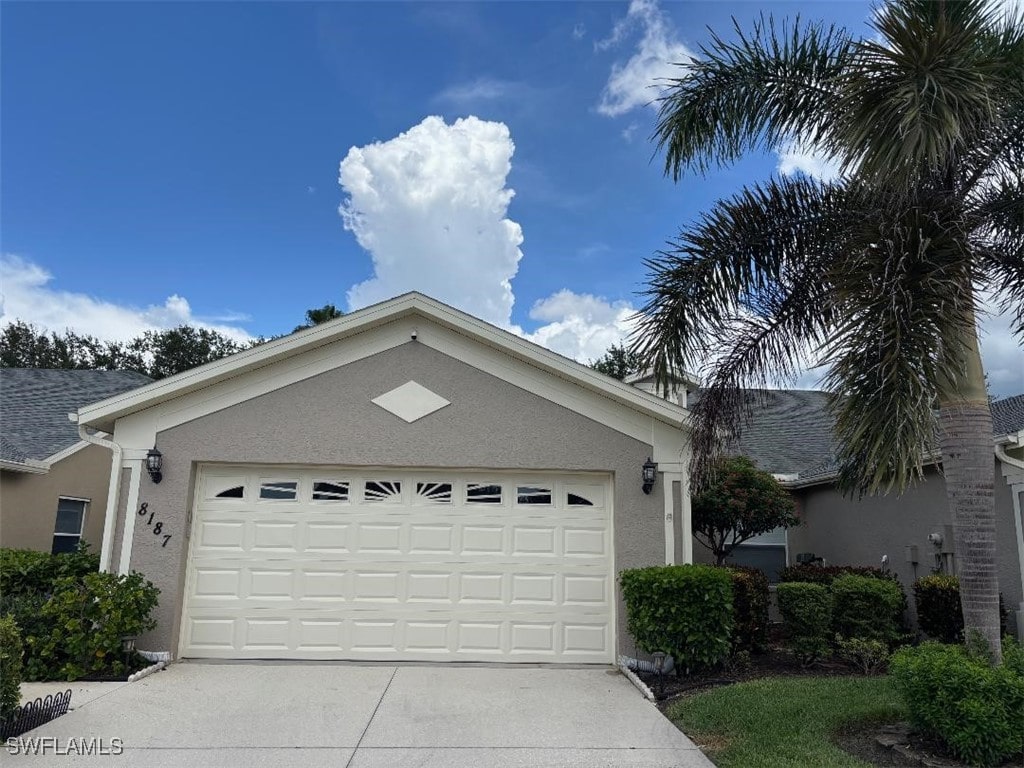 8187 Ibis Cove Cir Unit A113, Naples, FL 34119 - view of front of house with stucco siding, concrete driveway, and a garage