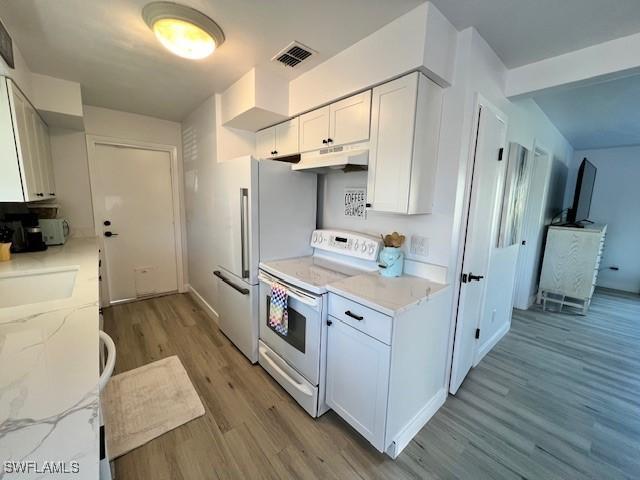 1661 Coronado Rd, Fort Myers, FL 33901 - kitchen featuring white appliances, under cabinet range hood, light wood-style floors, white cabinets, and light stone counters