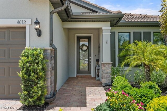 4012 E Hampton Cir, Alva, FL 33920 - view of exterior entry with stucco siding, a tiled roof, and a garage