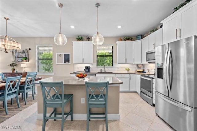 4012 E Hampton Cir, Alva, FL 33920 - kitchen featuring stainless steel appliances, a kitchen island, decorative backsplash, white cabinetry, and a breakfast bar area