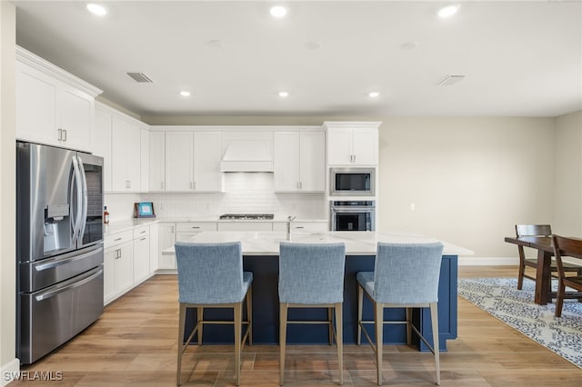 20676 Napa Loop, Estero, FL 33928 - kitchen with stainless steel appliances, custom exhaust hood, a breakfast bar, white cabinets, and recessed lighting