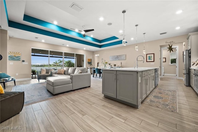 42274 Waterfront Way, Punta Gorda, FL 33982 - kitchen with gray cabinets, open floor plan, light countertops, a raised ceiling, and light wood-type flooring