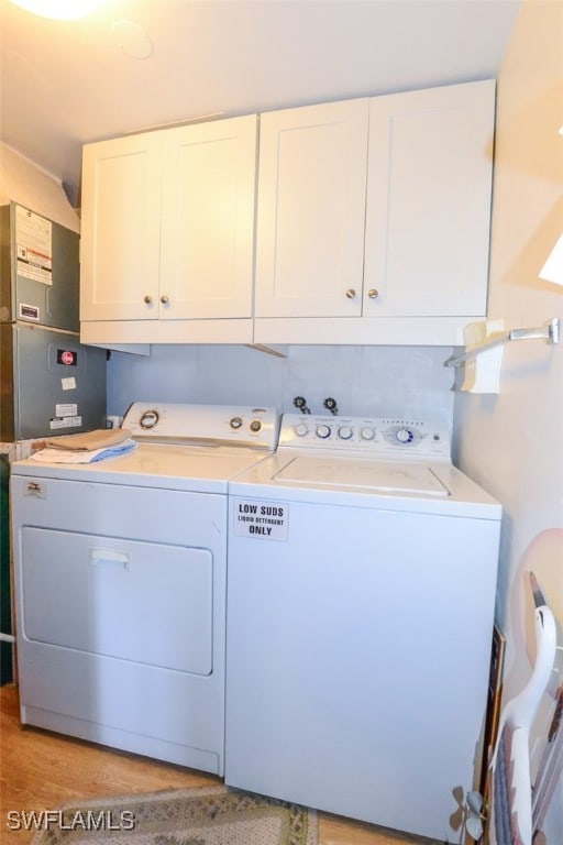 7000 Estero Blvd Unit 205, Fort Myers Beach, FL 33931 - laundry room featuring separate washer and dryer, cabinet space, and light wood-style floors