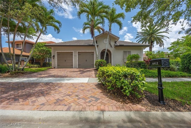 6912 Anthurium Ln, Naples, FL 34113 - view of front of house featuring stucco siding, decorative driveway, and a garage