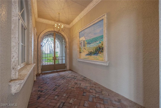 6912 Anthurium Ln, Naples, FL 34113 - foyer entrance featuring brick flooring, ornamental molding, a chandelier, a textured wall, and a textured ceiling
