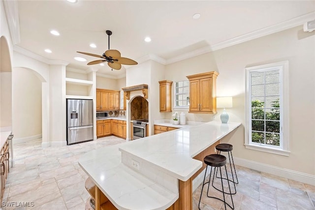 6912 Anthurium Ln, Naples, FL 34113 - kitchen with appliances with stainless steel finishes, arched walkways, a peninsula, a breakfast bar, and a ceiling fan