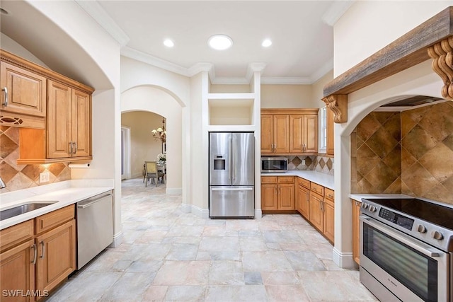 6912 Anthurium Ln, Naples, FL 34113 - kitchen featuring appliances with stainless steel finishes, arched walkways, light countertops, crown molding, and backsplash