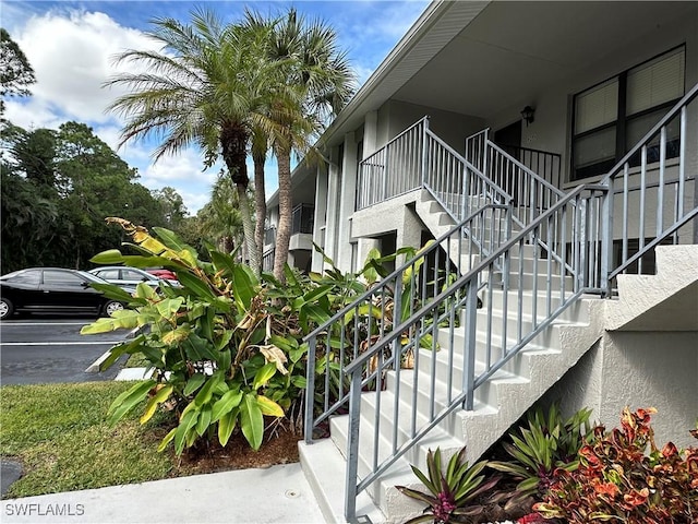 1224 Commonwealth Cir Unit N-203, Naples, FL 34116 - view of property exterior with stucco siding, uncovered parking, and stairs