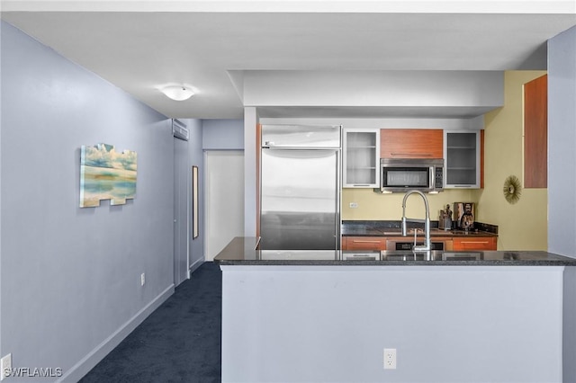 3000 Oasis Grand Blvd Unit 906, Fort Myers, FL 33916 - kitchen featuring appliances with stainless steel finishes, dark countertops, dark colored carpet, and glass insert cabinets
