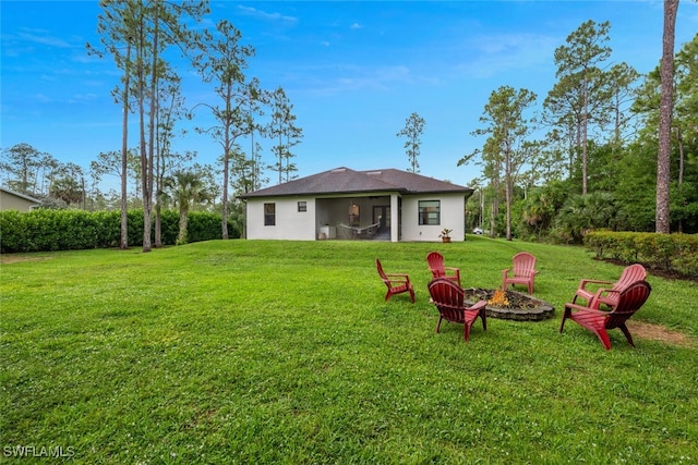 4345 6th Ave NE, Naples, FL 34120 - back of house with a fire pit, a lawn, and stucco siding