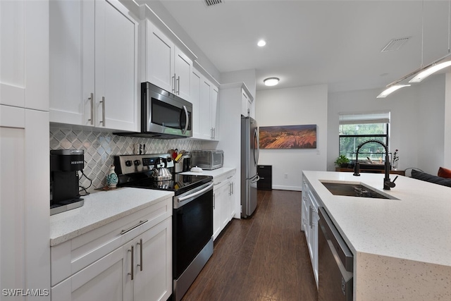 4345 6th Ave NE, Naples, FL 34120 - kitchen featuring stainless steel appliances, white cabinets, backsplash, dark wood-style flooring, and light stone counters