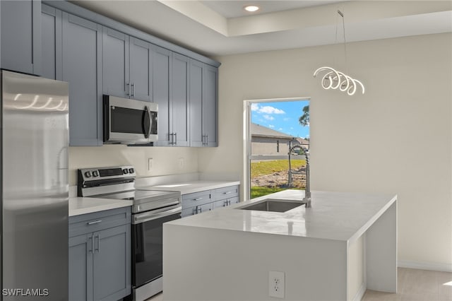 3211 8th St W, Lehigh Acres, FL 33971 - kitchen with appliances with stainless steel finishes, a center island with sink, light countertops, pendant lighting, and gray cabinetry