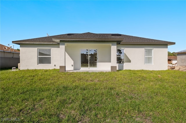 3211 8th St W, Lehigh Acres, FL 33971 - rear view of property featuring a lawn, stucco siding, and a shingled roof
