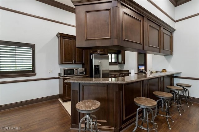 12970 Positano Cir Unit 301, Naples, FL 34105 - kitchen featuring stainless steel appliances, dark brown cabinets, dark wood-style floors, a kitchen breakfast bar, and dark stone counters