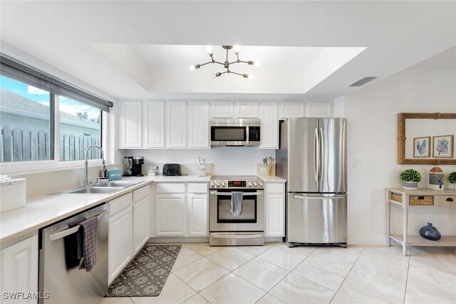636 98th Ave N, Naples, FL 34108 - kitchen with stainless steel appliances, a tray ceiling, a chandelier, and light countertops