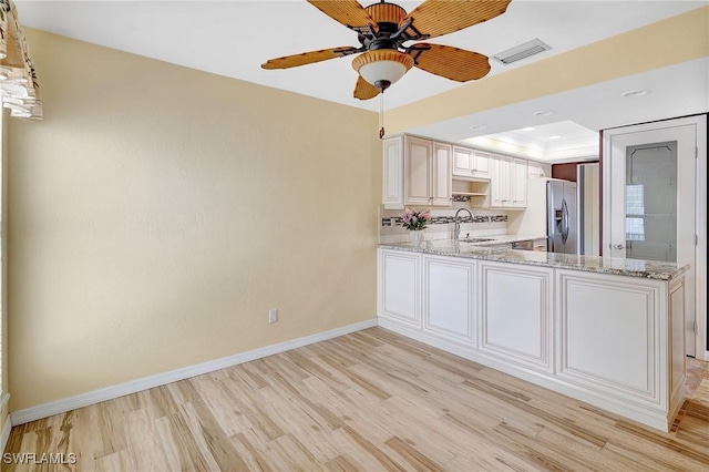4210 SE 20th Pl Unit C2, Cape Coral, FL 33904 - kitchen with stainless steel fridge, light wood-type flooring, a ceiling fan, light stone counters, and a tray ceiling