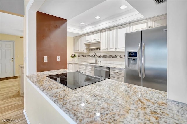 4210 SE 20th Pl Unit C2, Cape Coral, FL 33904 - kitchen featuring stainless steel appliances, a tray ceiling, decorative backsplash, light wood finished floors, and recessed lighting