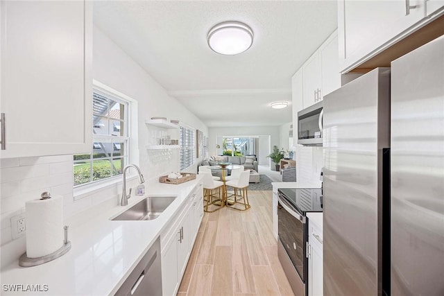 3070 Gulf Shore Blvd N Unit 104, Naples, FL 34103 - kitchen featuring stainless steel appliances, white cabinetry, open floor plan, light countertops, and backsplash