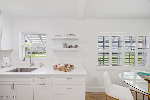 3070 Gulf Shore Blvd N Unit 104, Naples, FL 34103 - kitchen with plenty of natural light, white cabinetry, decorative backsplash, and beam ceiling