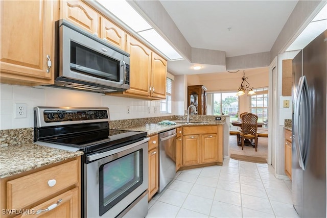 13221 Sherburne Cir Unit 601, Bonita Springs, FL 34135 - kitchen with appliances with stainless steel finishes, a peninsula, tasteful backsplash, and light stone counters