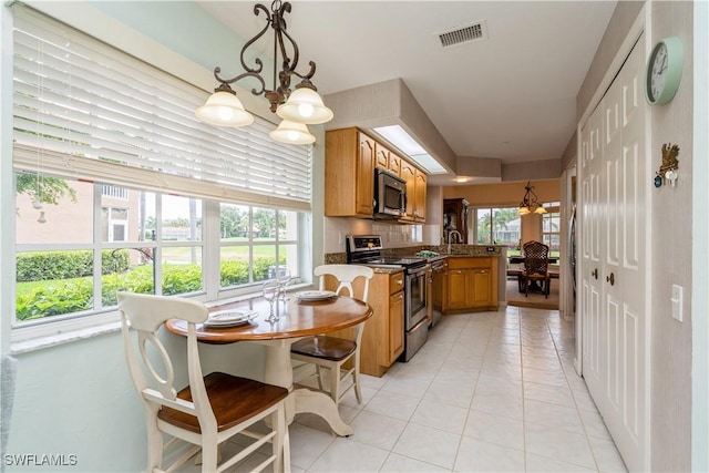 13221 Sherburne Cir Unit 601, Bonita Springs, FL 34135 - kitchen with appliances with stainless steel finishes, light tile patterned floors, a peninsula, brown cabinets, and decorative light fixtures