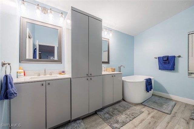 6011 Sea Grass Ln, Naples, FL 34116 - bathroom with double vanity, wood finished floors, and a freestanding bath