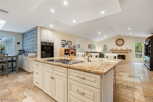 6011 Sea Grass Ln, Naples, FL 34116 - kitchen featuring stone tile flooring, black appliances, recessed lighting, a kitchen breakfast bar, and light stone counters