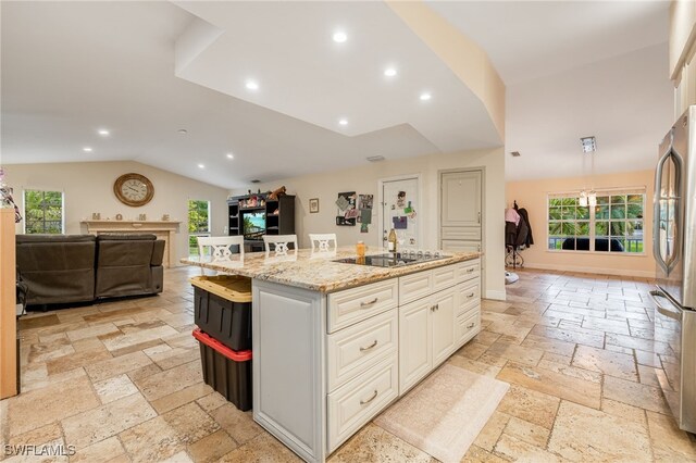 6011 Sea Grass Ln, Naples, FL 34116 - kitchen with stone tile floors, freestanding refrigerator, plenty of natural light, black electric cooktop, and vaulted ceiling