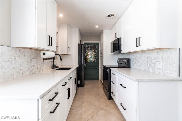 2401 Parkway St, Fort Myers, FL 33901 - kitchen featuring black appliances, light tile patterned floors, white cabinetry, tasteful backsplash, and light countertops