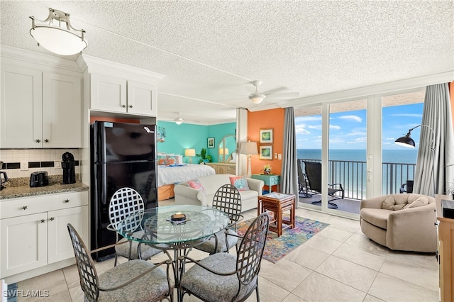 7360 Estero Blvd Unit Ph5, Fort Myers Beach, FL 33931 - dining space with a water view, a wall of windows, a textured ceiling, light tile patterned floors, and a ceiling fan