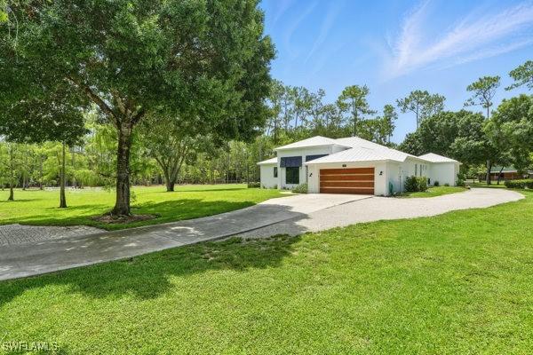 4740 5th Ave SW, Naples, FL 34119 - view of front facade featuring concrete driveway, an attached garage, and a front lawn